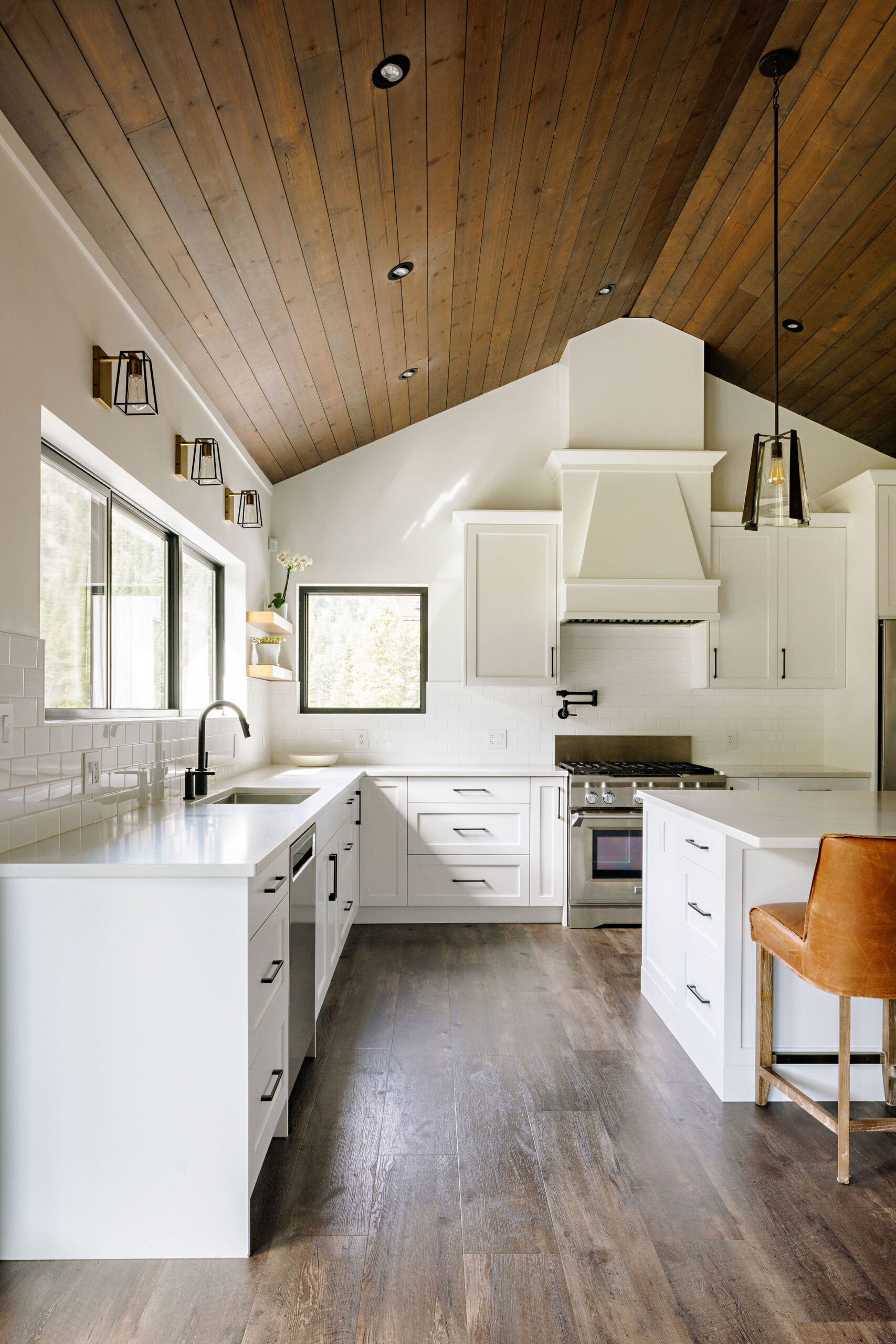 Image showing country kitchen with white cabinetry, large island additional sink and lots of counter space. There are lots of lower cabinets and above counter height is primarily windows.