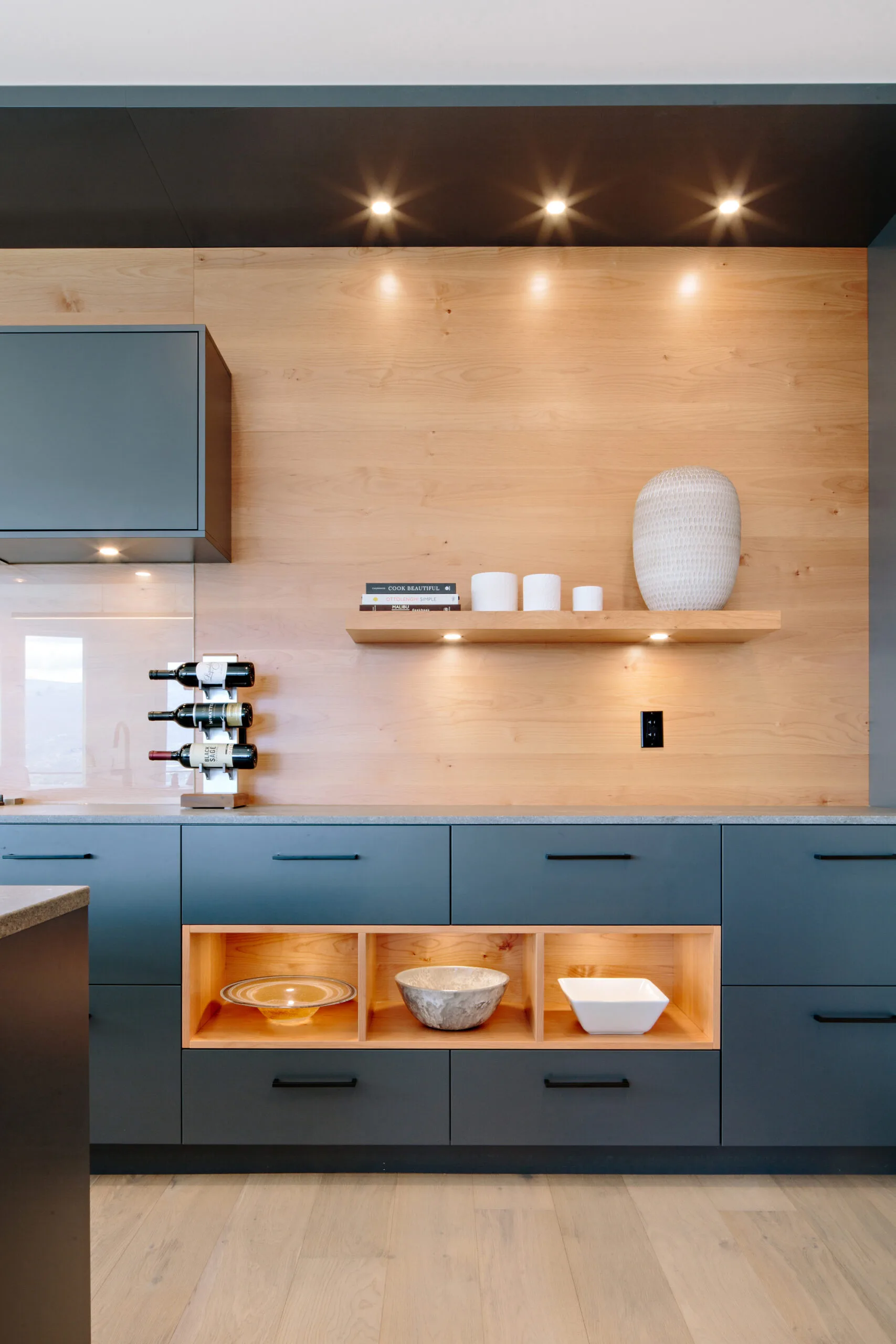 Image of grey kitchen cabinets with open shelving, overhead lights and natural wood accents. Built by Whitfield Homes