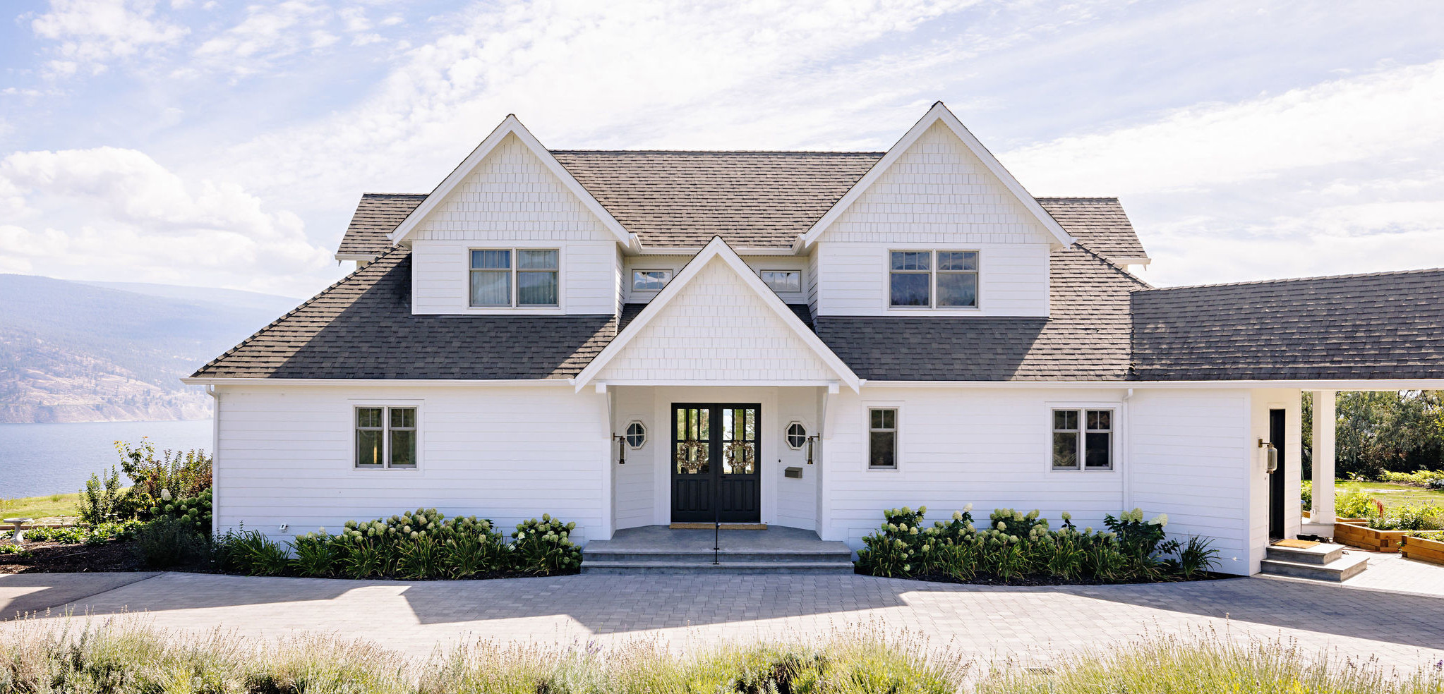Image of the exterior of a white farmhouse a separated garage connected by a covered walkway.