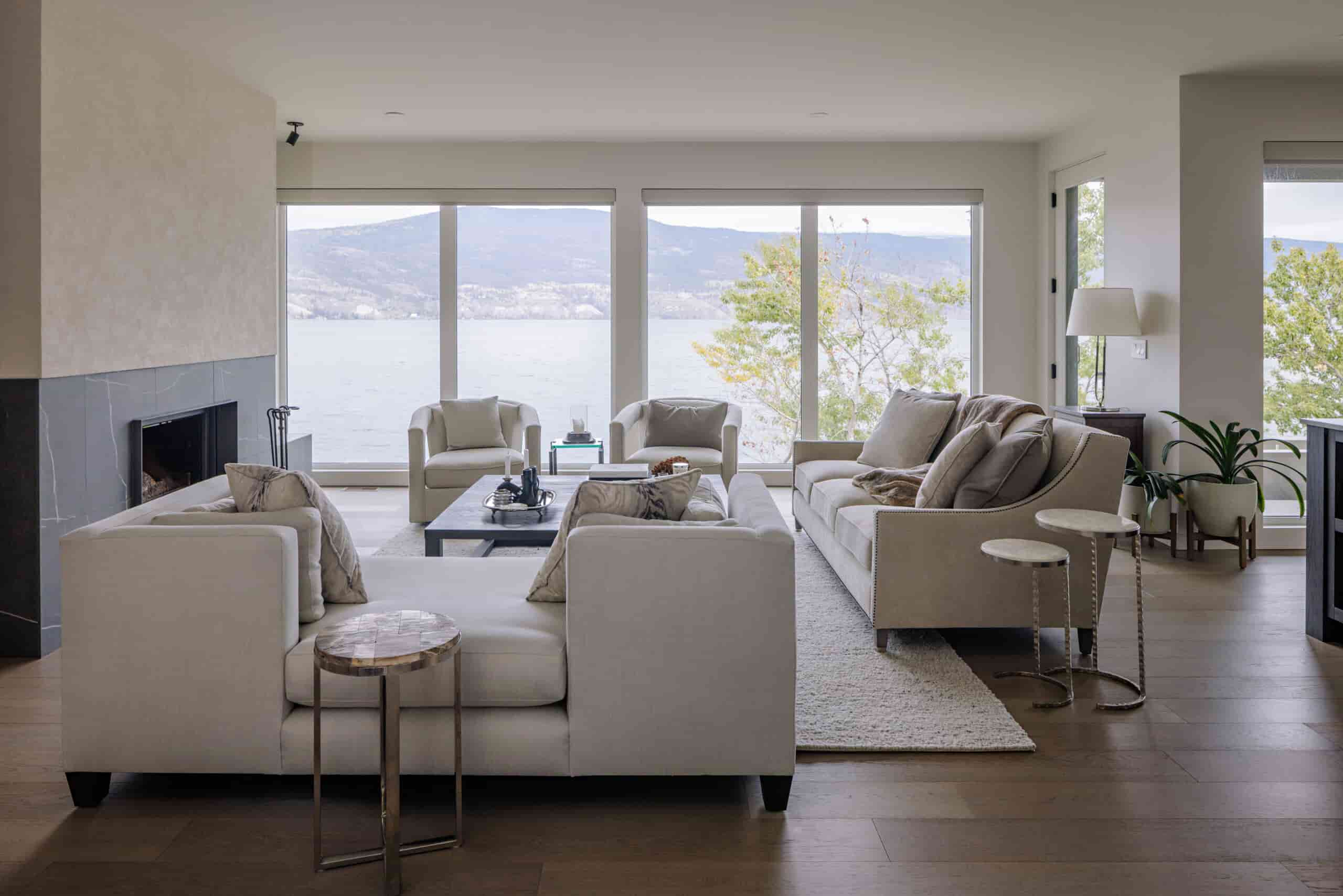 Bright custom home living room with large windows overlooking the lake and surrounding hills