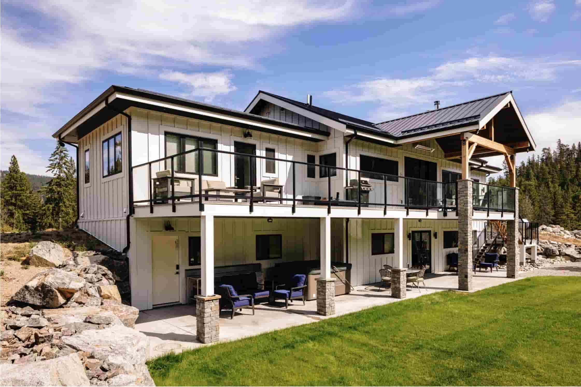 Modern custom home with a metal roof, covered patio and glass-railed balcony