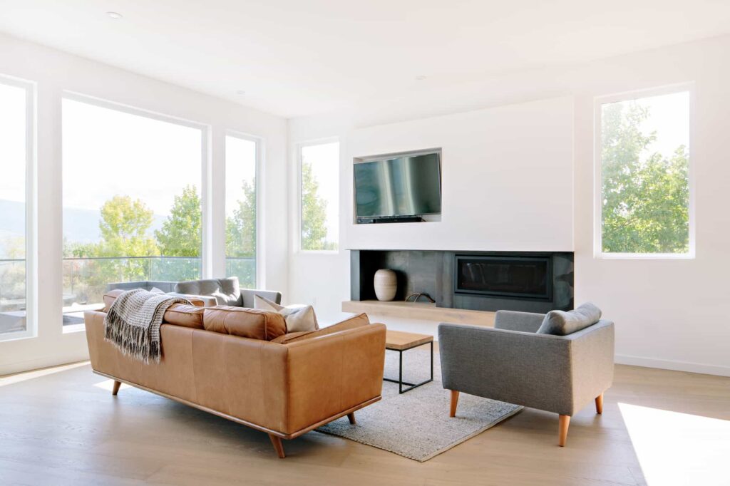 Bright modern living room with large windows, a fireplace and neutral seating