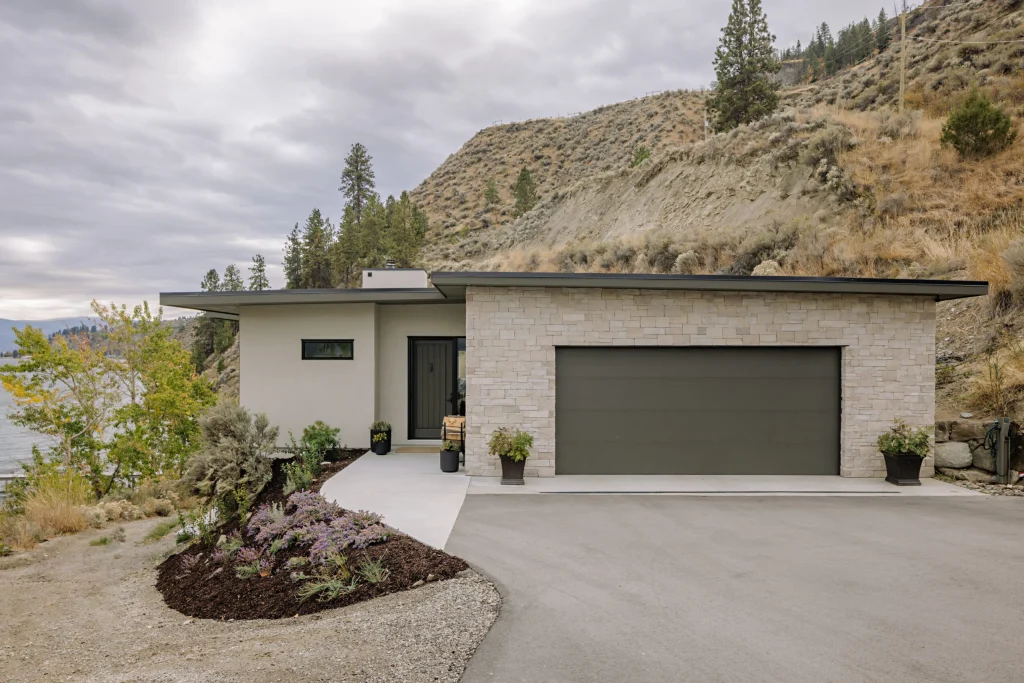 Callan entrance and double garage beside a rocky hillside, with planting beds along the driveway