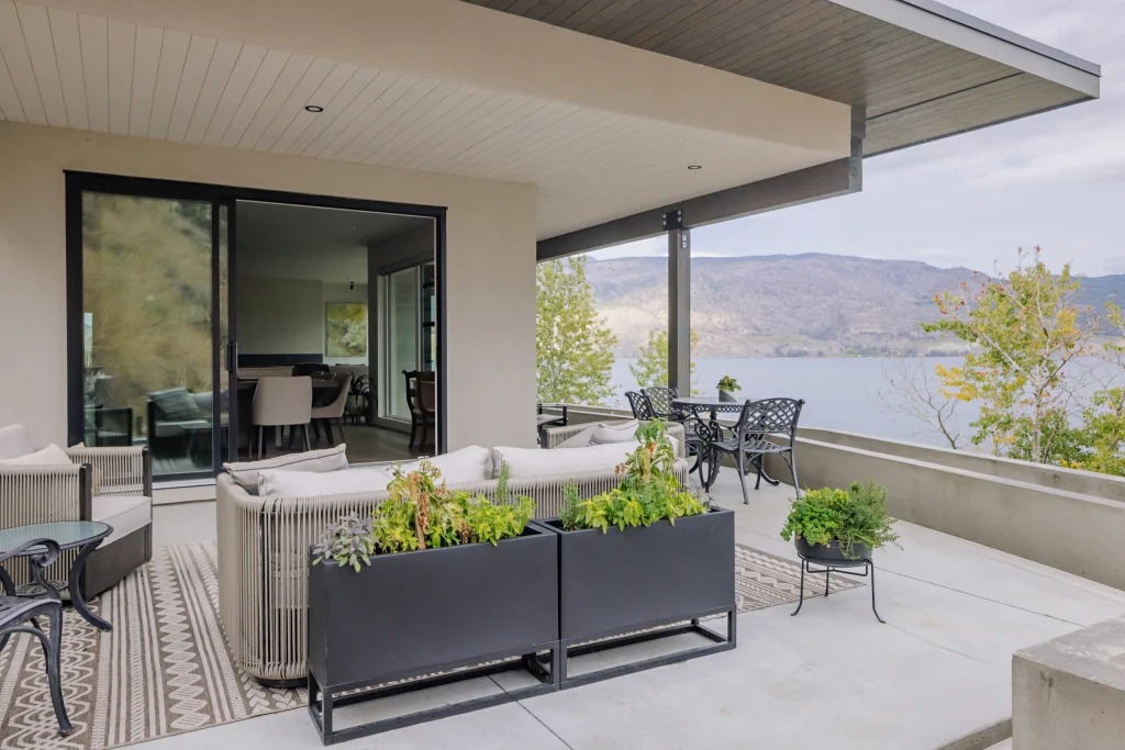 Covered terrace at Callan with outdoor seating, planters and views of the lake and hills