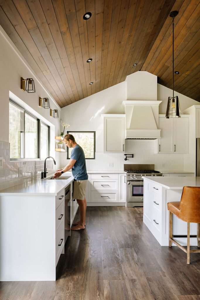 Fish Lake kitchen with a sloped wood ceiling, white cabinets and a long window above the sink