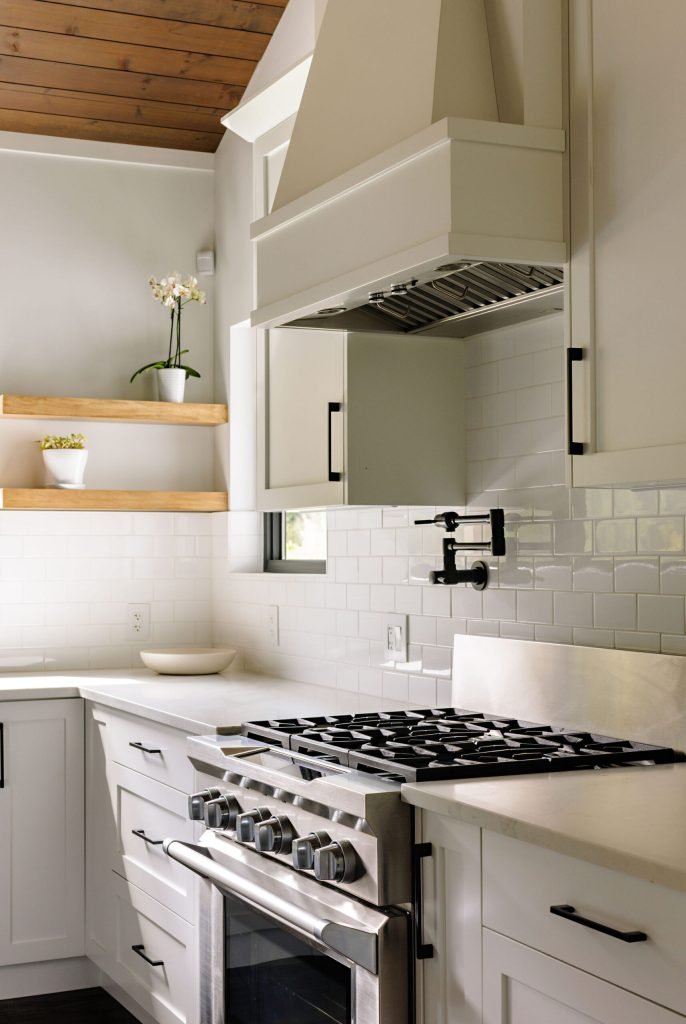 Fish Lake kitchen range with a white hood, tile backsplash and wood ceiling