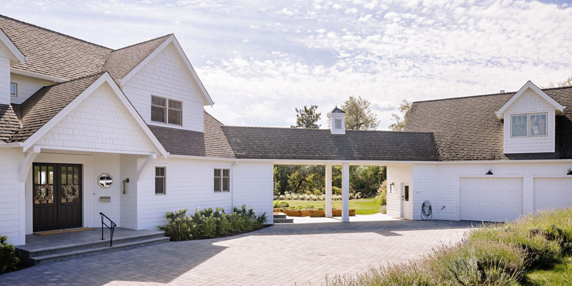 Image of the exterior of a white farmhouse a separated garage connected by a covered walkway.